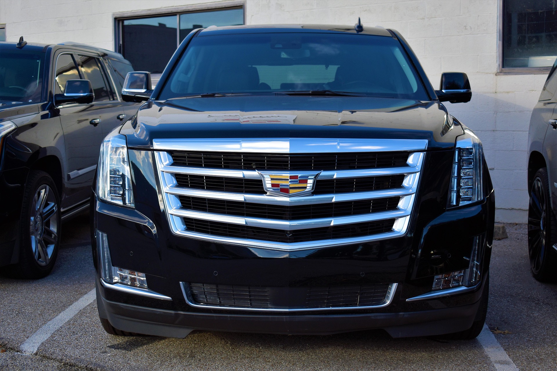 A black Cadillac Escalade luxury SUV from the Orlux Partner Network parked in front of a modern executive terminal.