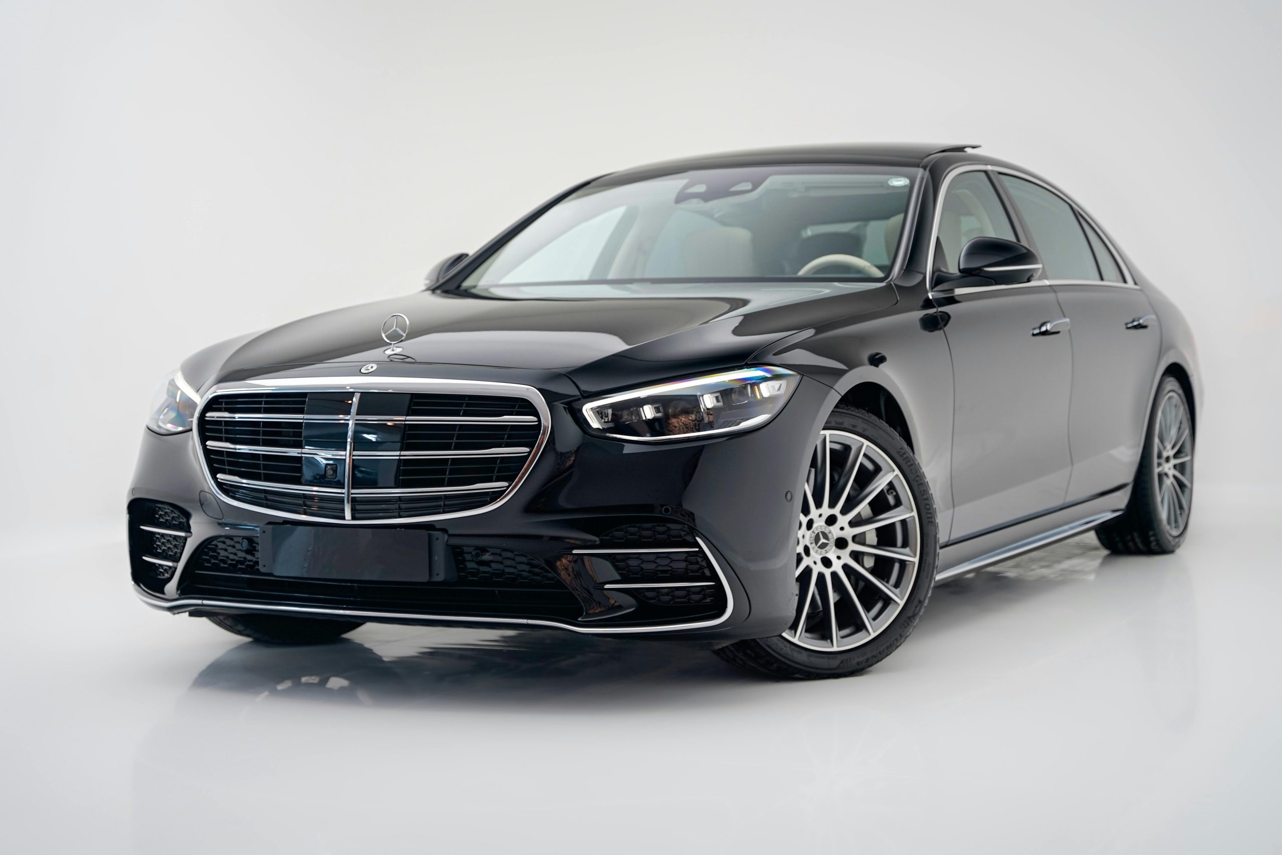 A sleek black Mercedes-Benz S-Class luxury sedan for executive transportation parked in a brightly lit white studio.