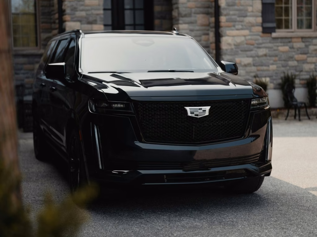 Black full-size luxury SUV parked in front of a stone house with arched windows
