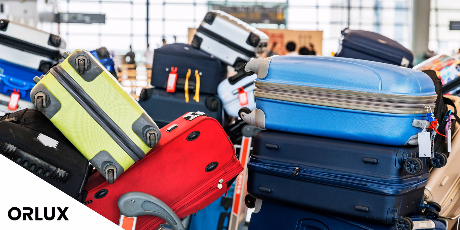 A heap of hard-shell suitcases in bright colors stacked in a busy airport hall